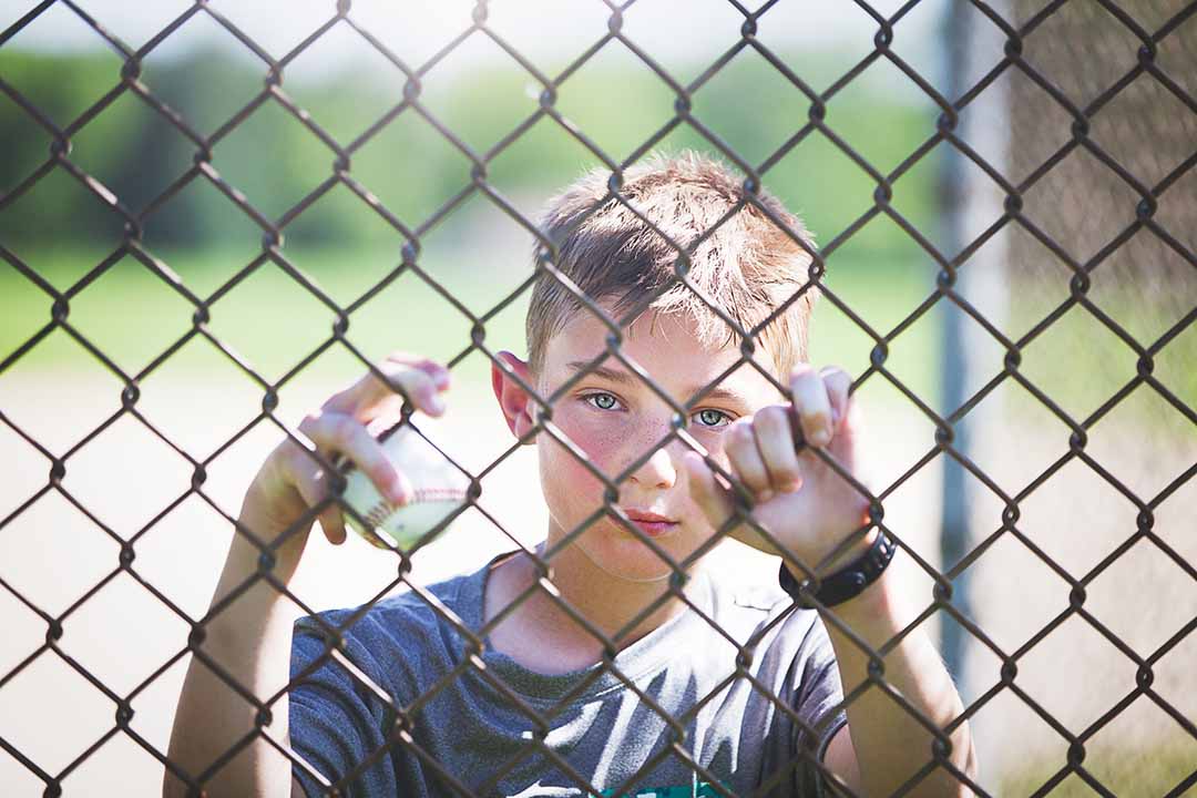 boy looking through a fence