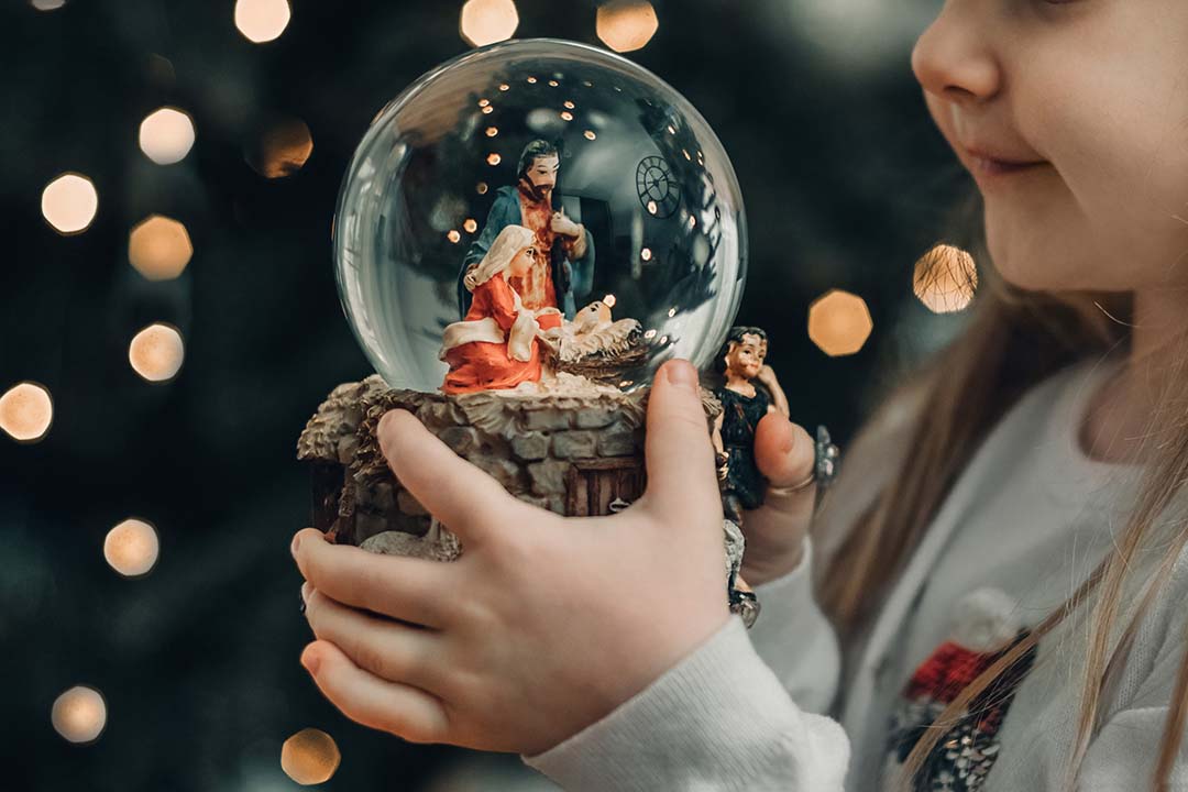 girl looking at a manger scene inside a glass globe